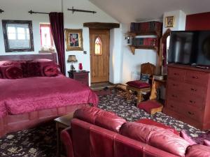 a bedroom with a bed and a couch and a tv at Peak District Cottage set in 5 acres near Buxton in Buxton