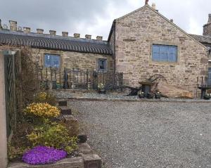 a stone house with a fence and flowers in front of it at Peak District Cottage set in 5 acres near Buxton in Buxton