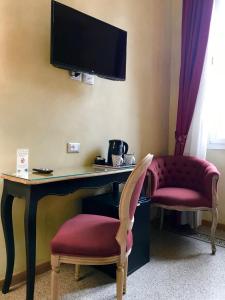 a desk with two chairs and a tv on a wall at Guest House Le Contesse in Florence