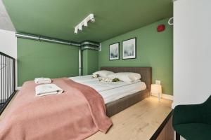 a bedroom with green walls and a bed with a pink blanket at Airport Studio Zarembowicza by Noclegi Renters in Wrocław +71 photos