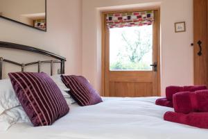 a bedroom with a bed with purple pillows and a window at Country Cottage with Hot Tub - pre-heated for your arrival in Buxton