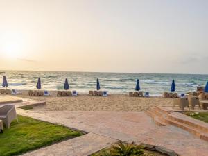 uma praia com cadeiras e guarda-sóis e o oceano em Helnan Mamoura Hotel & Events Center em Alexandria