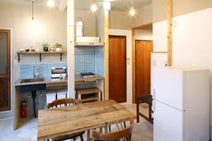 eine Küche mit einem Holztisch und einem Kühlschrank in der Unterkunft Tokyo Hikari Guesthouse in Tokio
