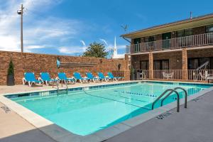 a swimming pool with blue chairs and a building at Quality Inn Magnolia in Magnolia