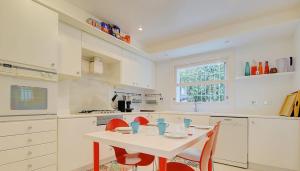 a white kitchen with a table and red chairs at VILLA BONANOVA STYLE in Palma de Mallorca