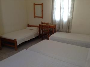 a room with two beds and a chair in it at Rooms to let Katerina & John's in Perissa