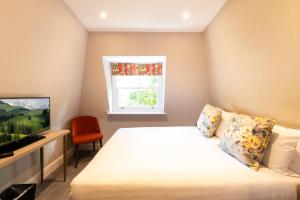 um quarto com uma cama, uma televisão e uma janela em Byron Hotel em Londres