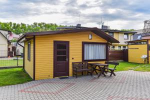 a small yellow shed with a table and a bench at Namelio nuoma in Palanga