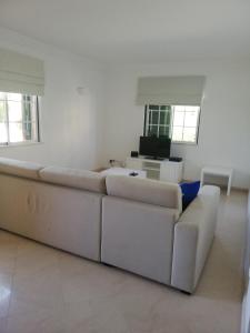 a white living room with a couch and a tv at Villa V2 U in Olhos de Água
