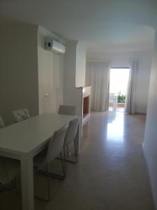 a dining room with a white table and chairs at Villa V2 U in Olhos de Água