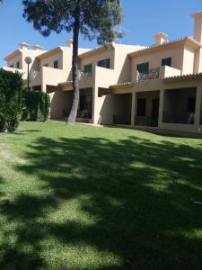 a large building with a tree in the yard at Villa V2 U in Olhos de Água