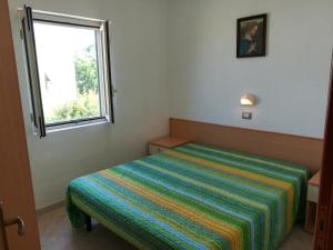 una piccola camera da letto con un letto con una coperta colorata di Holidays in Vieste in charming villas - 2 a Vieste
