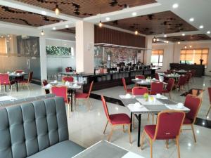 a dining room with tables and red chairs at UNP Hotel & Convention in Padang