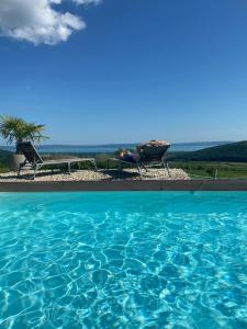 a person laying in chairs next to a swimming pool at Panorama, Balaton in Dörgicse