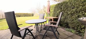 drie stoelen en een tafel op een patio bij Boddenhus Rügen - Fewo Möwe in Breege