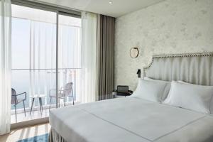 a bedroom with a large white bed and a balcony at ON Residence - Small Luxury Hotels of the World in Thessaloniki