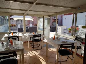 un restaurante con mesas y sillas blancas y ventanas en Bed and Breakfast I Vicoletti Di Napoli, en Nápoles