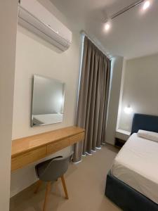 1 dormitorio con escritorio, 1 cama y espejo en Heaven Residence - Green Coast Resort, Palasë en Llogara