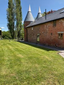 a brick building with two towers on a grass field at The Hophouse in Hereford