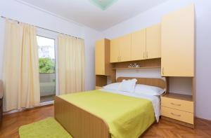 sypialnia z dużym łóżkiem i żółtym kocem w obiekcie Apartments Villa Vujcic w Makarskiej
