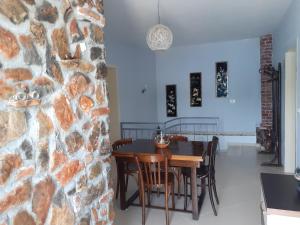 una sala da pranzo con parete in pietra, tavolo e sedie di Nesti Relax Home a Pogradec