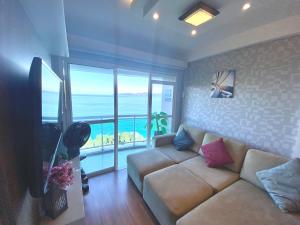 a living room with a couch and a view of the ocean at Porto Real Suites Apto de frente p/mar in Mangaratiba