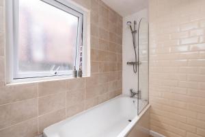 a bathroom with a bath tub and a window at Spacious 5 Bed House, perfect for groups, great location in Liverpool