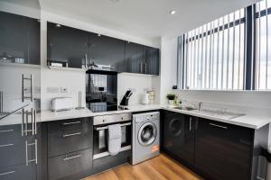 een keuken met zwarte kasten en een wasmachine en droger bij City View Apartment in Liverpool