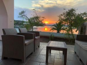 a patio with chairs and a table and a sunset at Sunset Bay in Porto Heli