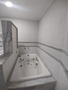y baño con una gran bañera blanca con espejo. en Horto Executivo Hotel, en Ipatinga