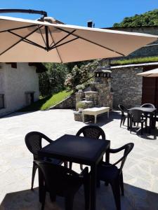 una mesa, sillas y una sombrilla en el patio en Affittacamere La Lea, en Roccaforte Mondovì