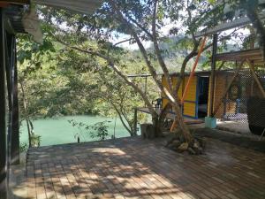 uma casa com uma árvore em frente a um corpo de água em Room in Cabin - Rafting Hut by The River em Lanquín