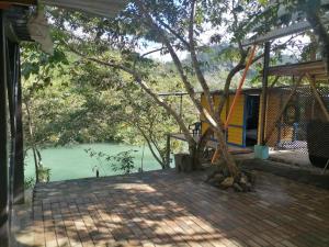 a house with a tree in front of a body of water at Rafting Hut by The River in Lanquín