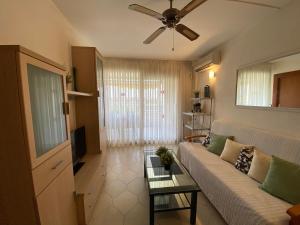 uma sala de estar com um sofá e uma ventoinha de tecto em Apartamento con piscina en 1ª línea de playa en Salou em Salou