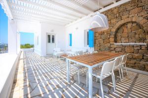 a dining room with a wooden table and white chairs at Adikri Villas & Suites in Tourlos