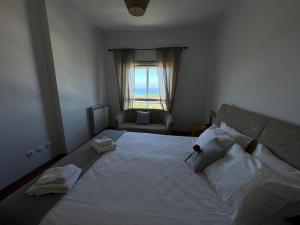 ein Schlafzimmer mit einem großen Bett mit einem Stuhl und einem Fenster in der Unterkunft Amazing Lodge by the Ocean - Fully equipped! in Ericeira