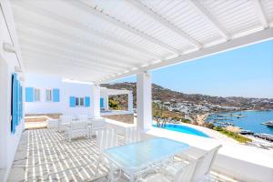a white patio with a glass table and white chairs at Adikri Villas & Suites in Tourlos