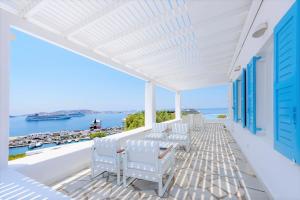 einen Balkon mit weißen Stühlen und Blick auf das Wasser in der Unterkunft Adikri Villas & Suites in Tourlos