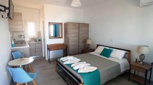 a bedroom with a bed and a table and a kitchen at Evilion Donoussa Studios in Donoussa