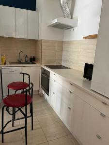 a kitchen with white cabinets and two red chairs at Apartament Lux 2 camere Nordului in Bucharest