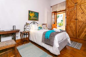 een slaapkamer met een bed, een tafel en een raam bij Ravenscliff Manor in Oudtshoorn