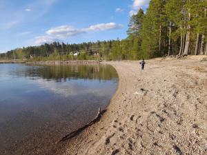 a person fishing on the shore of a lake at Single bedroom, outside toilet, shower, kitchen. 120 m from Sandbach in Bräcke