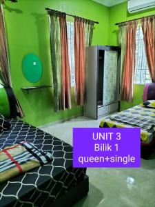 a bedroom with two beds and green walls at Homestay D ARYNIE in Bukit Payong