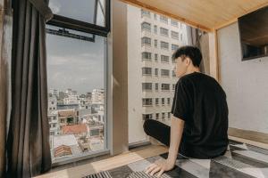 a man sitting on the floor looking out of a window at IKIGAI Dorm Hostel - Danang Centre in Da Nang