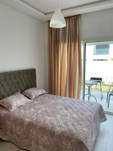 a bedroom with a bed and a balcony with a table at Lovely 4-bedroom condo with pool in Rabat
