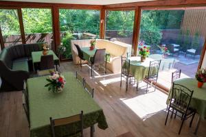 a conservatory with tables and chairs in a room with windows at Pensiunea Verde in Baia-Sprie