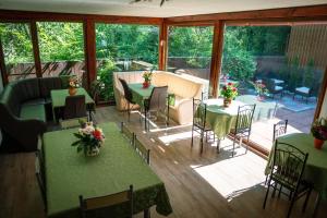 un salón acristalado con mesas y sillas y un patio en Pension Verde, en Baia-Sprie