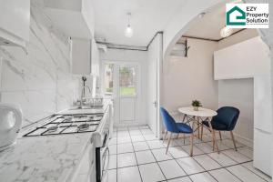 a kitchen with a stove and a table with chairs at Ezy Property Solution Short Lets & Serviced Accommodation Norbury in London
