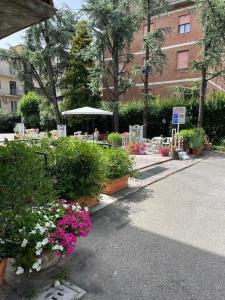 un jardín con mesas, sillas y flores en Hotel Astor, en Módena