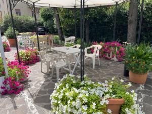 un patio con mesa, sillas y flores en Hotel Astor, en Módena